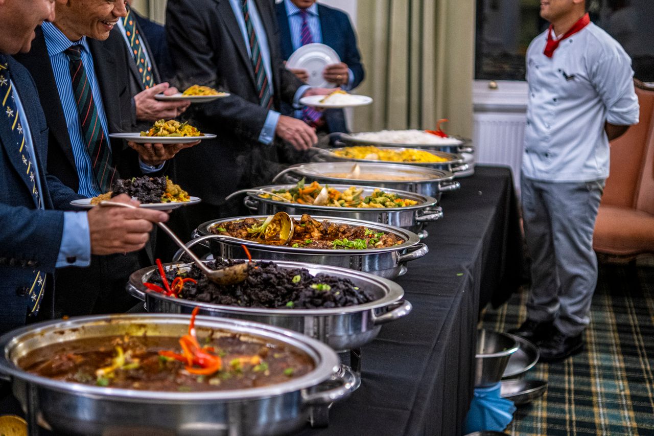 who-we-are Business professionals in suits enjoy a diverse buffet lunch selection at a formal event.