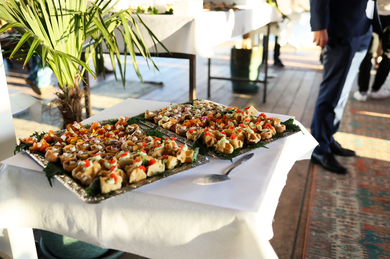 about-us Gourmet appetizers at a stylish indoor event with attendees in formal attire.