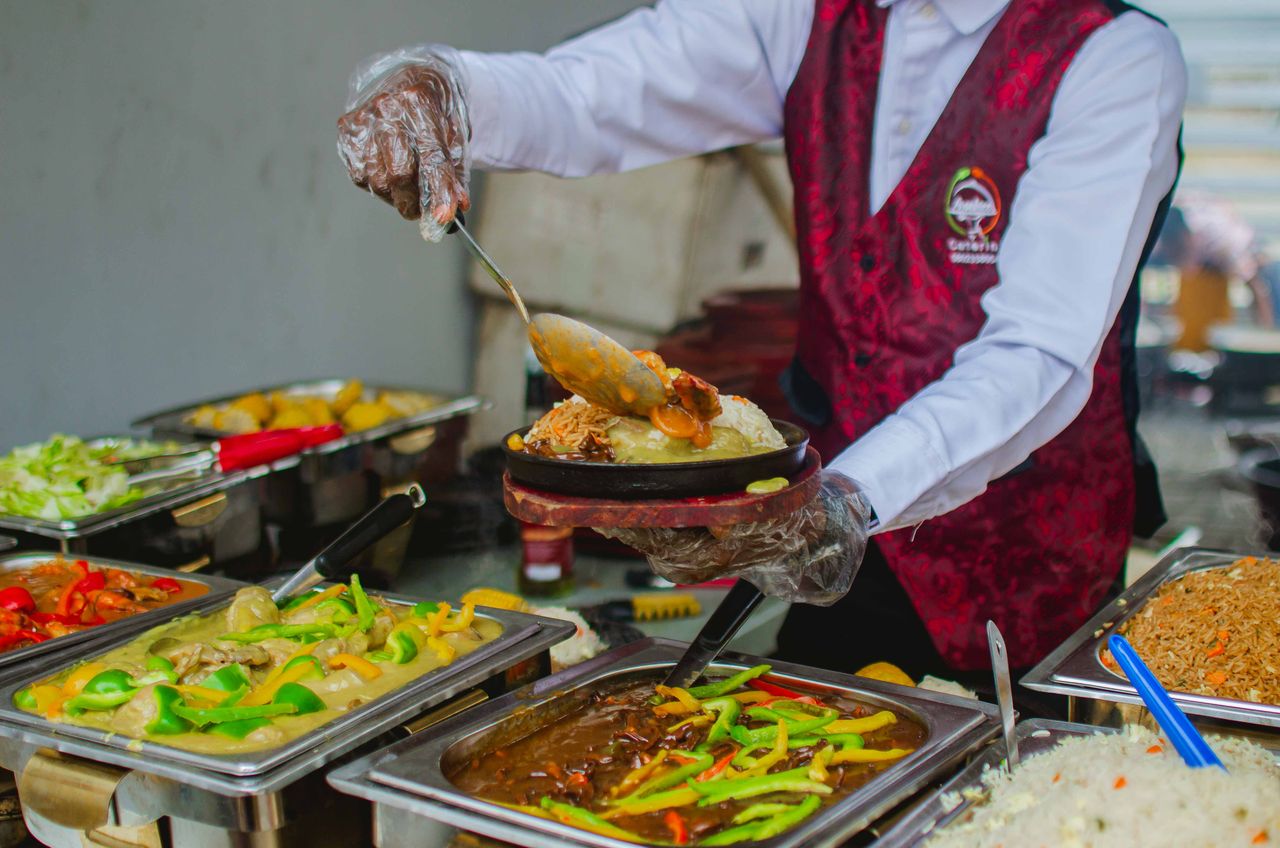 Mastering the First Impression: Your intriguing post title goes here A chef expertly serves a variety of colorful dishes at a buffet, highlighting culinary expertise.